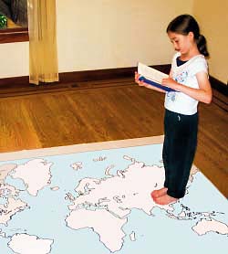 Girl walking on a map of the continents, reading a book.